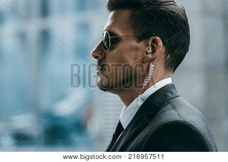 profile of handsome bodyguard with sunglasses and security earpiece