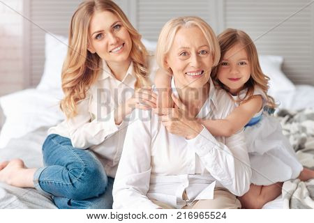 Time together. Joyful positive elderly woman smiling and feeling happy while spending time with her family