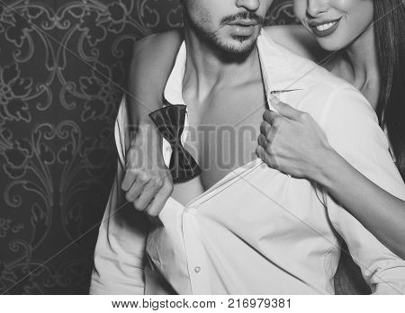 Sexy woman undressing trendy macho man indoor foreplay black and white