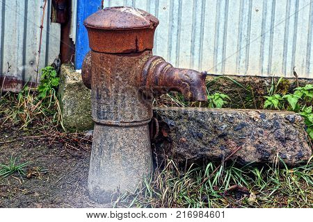 old iron column for water on the street near the fence