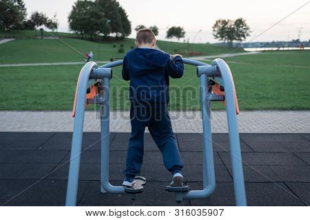 Street Workout Equipment Outdoor Sport Fitness And Bodybuilding. Boy In A Sport Playground Doing Wor