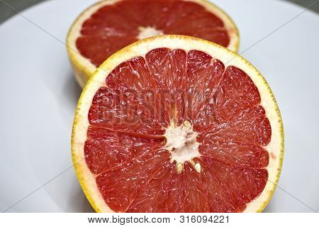 Two Pink Grapefruit Halves On White Plate.