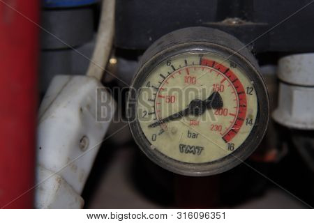 The Pressure Gauge On An Air Compressor In A Messy Garage.