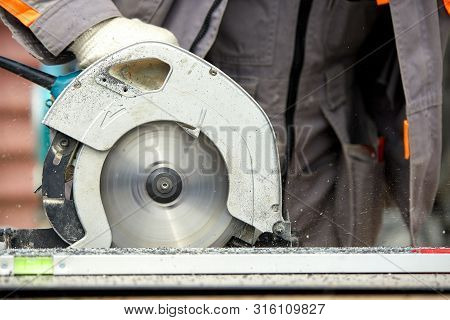 A Construction Contractor Worker Using A Worm-driven Hand-held Circular Saw To Cut Boards And Plasti