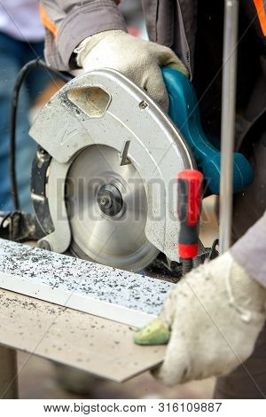 A Construction Contractor Worker Using A Worm-driven Hand-held Circular Saw To Cut Boards And Plasti