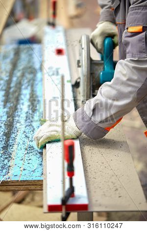 A Construction Contractor Worker Using A Worm-driven Hand-held Circular Saw To Cut Boards And Plasti
