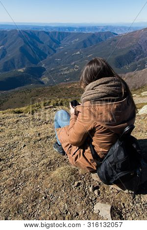 Beautiful Woman Sitting After Hiking With The Phone During Winter Or Autumn In Catalonia (turo Del H