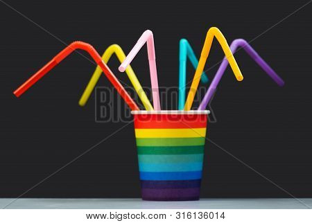 A Color Paper Cup Like A Rainbow With Many Multi-colored Cocktail Tubes On A Gray Background. Select