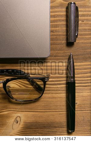 Notebook, Laptop, Glasses And Pen On The Table.