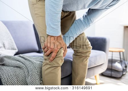 Man Suffering From Knee Pain While Trying To Stand Up