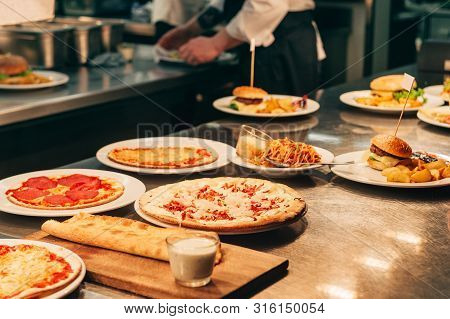 Food Orders On The Kitchen Table In The Restaurant, Pizza, Flammkuchen And Garlic Bread