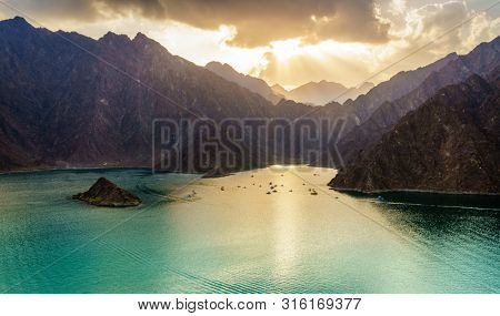Scenic view of Hatta Lake and Hajar Mountains in the Emirate of Dubai, UAE at sunset