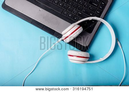 White Red Music Headphones On Technology Background Notbook Computer On A Blue Background. Happy Hol
