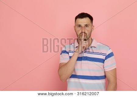 Secret Guy. Man Saying Hush Be Quiet With Finger On Lips Gesture Looking At Camera Isolated On Pink 
