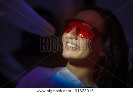 Close-up Portrait Of A Female Patient At Dentist In The Clinic. Teeth Whitening Procedure With Ultra