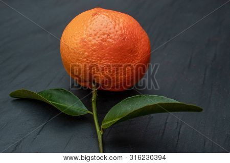 Orange Mandarin Fruit With Green Leaves On A Slate