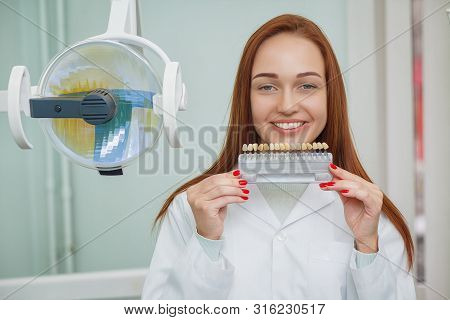 Closeup Of A Girl With Beautiful Smile At The Dentist. Dental. Dentist Matching Teeth Colour In Offi