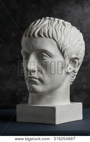 Gypsum Copy Of Ancient Statue Germanicus Head On Dark Textured Background. Plaster Sculpture Man Fac
