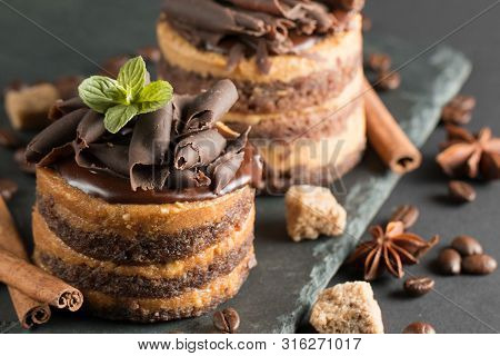 Dark Chocolate Cakes On Black Slattern Board With Mint, Cinnamon, Coffee Beans On A Wooden  Backgrou
