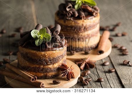 Dark Chocolate Cakes On Black Slattern Board With Mint, Cinnamon, Coffee Beans On A Wooden  Backgrou