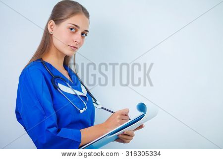 Doctor With A Stethoscope, Holding A Notebook In His Hand. Close-up Of A Female Doctor Filling Up Me