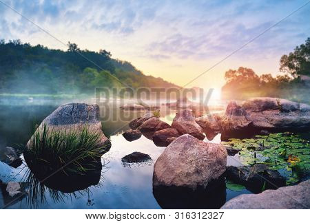 Landscape with sunrise and mist over river matutinal picturesque morning sky clouds in water sunbeam forest.