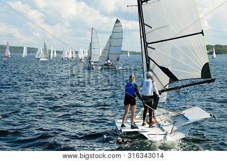 Children Sailing Small  Boat With A Closup Stern View Of One Dinghy In The Foreground With Many Othe