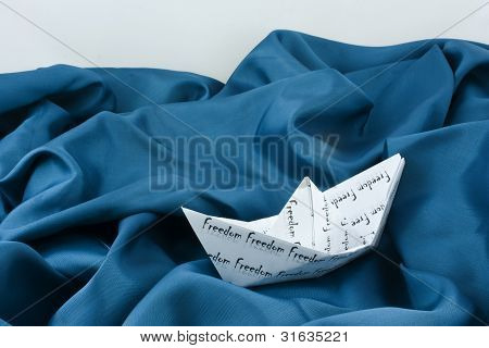 Papier Schiff in einem Ozean aus Stoff