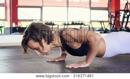 Sporty Woman Is Doing Set Of Reps Press-ups From The Floor In Gym. She Is Spreading Her Arms Wider A
