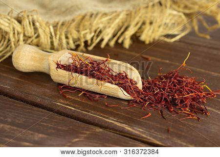 Lot Of Whole Dry Shaffron Thread Heap Near With Wooden Scoop And Jute Cloth On Brown Wood