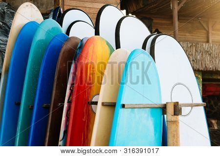 Set Of Different Color Surf Boards In A Stack By Ocean.bali.indonesia. Surf Boards On Sandy Beach Fo