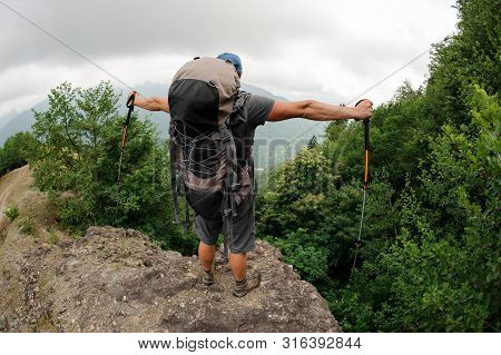 Male Tourist With Backpack Stands On Hill