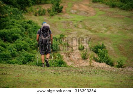 Male Tourist With Backpack Walking In Valley