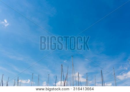 Many Topmasts Of Parking Sailing Yachts Against Blue Sky At Lake Balaton.