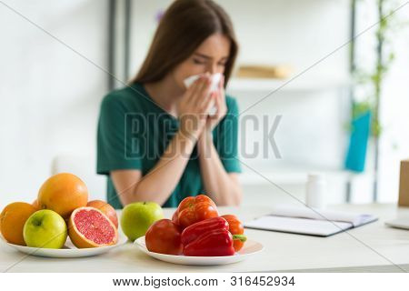 Selective Focus Of Woman Sitting At Table With Vegetables, Fruits And Pills And Using Napking While 