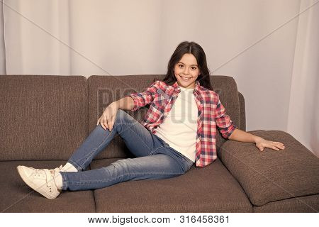 Happy Little Girl At Home. Childrens Day. Happy Child Relax On Sofa. Casual Childrens Fashion. Littl