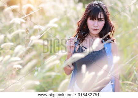 Young And Cute Girl Having A Happy Time And Enoying Amoung Grass Field In Nature