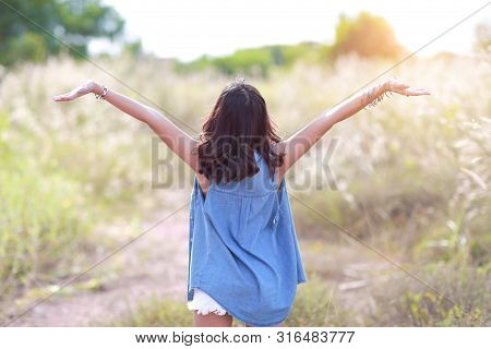 Young And Cute Girl Having A Happy Time And Enoying Amoung Grass Field In Nature