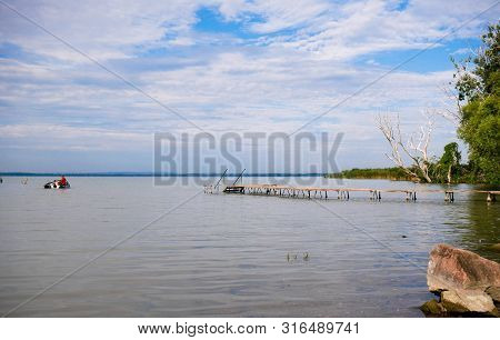 Empty Wood Deck At Balaton Lakeshore In The Morning Hours Passing Boat .