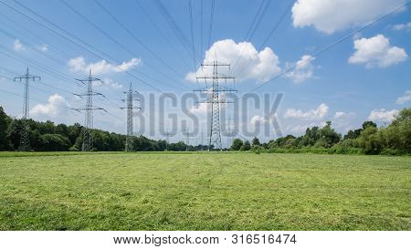 Electricity Pylons In The Freshly Mowed Floodplains.