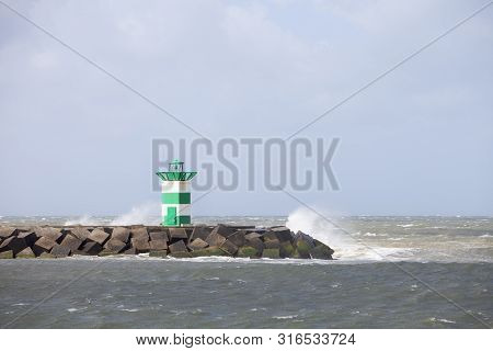 Water Splashes Over Lighthouse And Pier Near Scheveningen Harbor In The Netherlands During Summer St