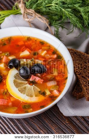 Traditional Russian Meat Soup Solyanka In Bowl On Rustic Wooden Table