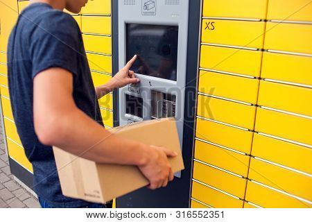 Client Using Automated Self Service Post Terminal Machine Or Locker To Deposit A Parcel For Storage