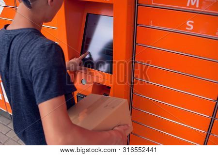 Client Using Automated Self Service Post Terminal Machine Or Locker To Deposit A Parcel For Storage