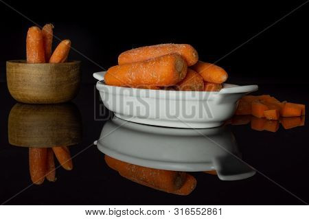 Lot Of Whole Stale  Orange Stale Baby Carrot Baby In A Wooden Bowl Isolated On Black Glass