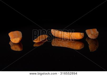 Group Of Four Halves Of Stale  Orange Stale Baby Carrot Baby Isolated On Black Glass