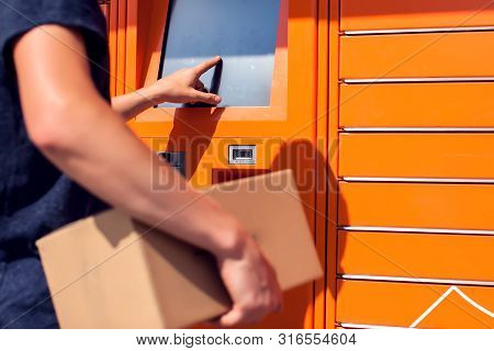 Man Using Automated Self Service Post Terminal Machine Or Locker To Deposit The Parcel For Storage