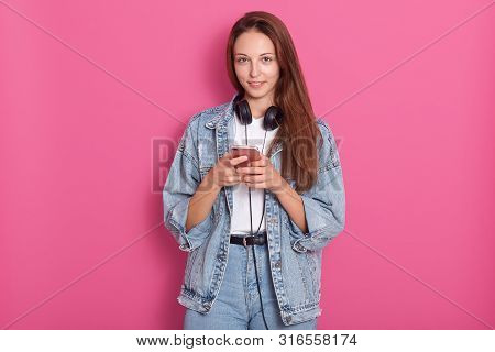 Portrait Of Happy Beautiful Young Lady Using Her Phone, Looking Directly At Camera And Smilng, Weari