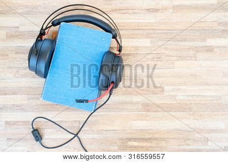Audio Book Concept. Black Headphones And Pile Of Books On Wooden Table. Top View With Copy Space.
