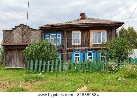 Russian Village In Summer. Old Wooden House With Blue Window Shutters. Village Of Visim, Sverdlovsk 